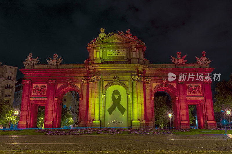 Puerta de Alcalá, in the Plaza de la Independencia in the city of Madrid, illuminated with the red and yellow colors of the Spanish flag